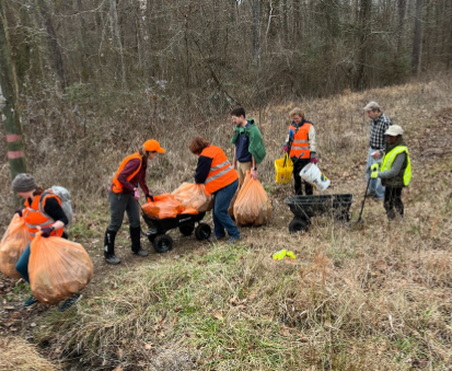 A group of volunteers in orange vests loading garbage bags full of trash into wagons.