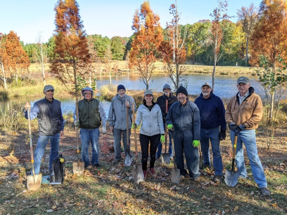 A group of South Wake Conservationists volunteers poses with their shovels at a tree planting.
