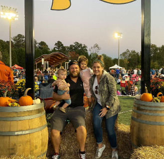 A family sits on a hay bale posing for a picture at Laketober Music Festival.