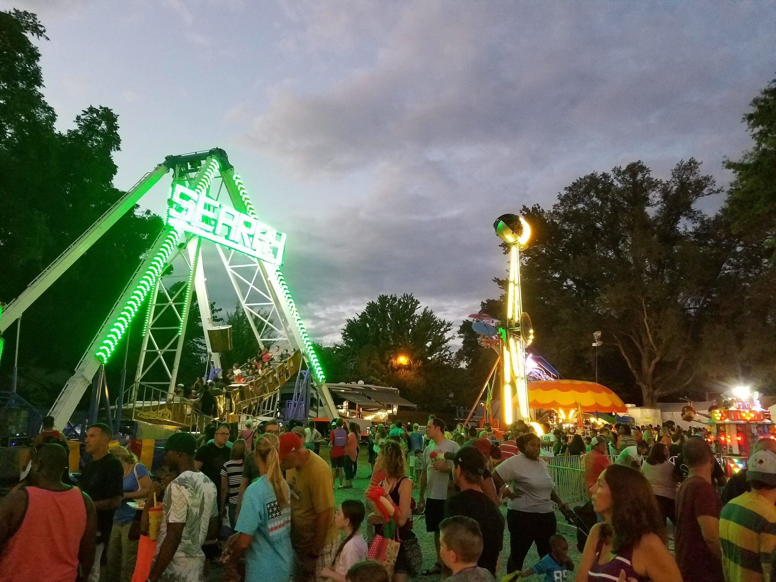 The Matthews Alive carnival rides surrounded by crowds of people.