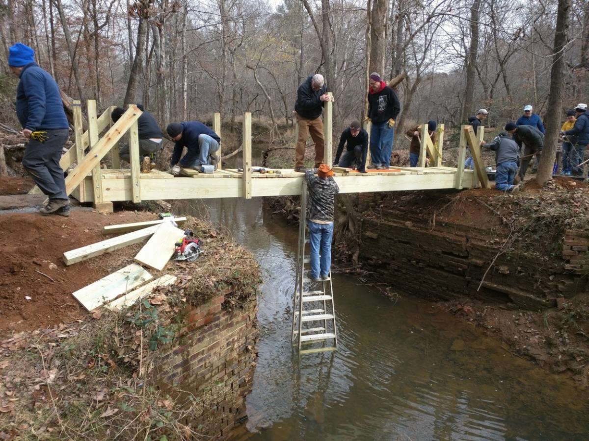 volunteers erect a wooden bridge over Cates Creek