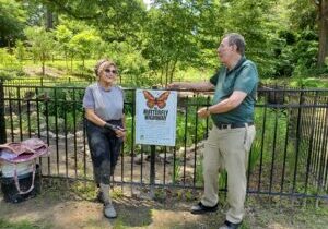 Neuse River Hawks chapter members flank a Butterfly Highway sign at Forest Ridge Park pollinator garden