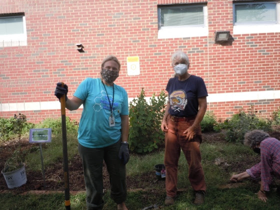 Two volunteers standing with garden tools at the Millbrook Elementary garden.
